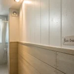 Lambris dans une salle de bain : PVC blanc et bois traité, zones humides