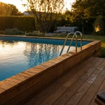 Piscine hors sol bois avec terrasse : vue jardin au golden hour