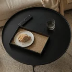 Table basse noire ronde avec tiroirs ou réhausse près du canapé
